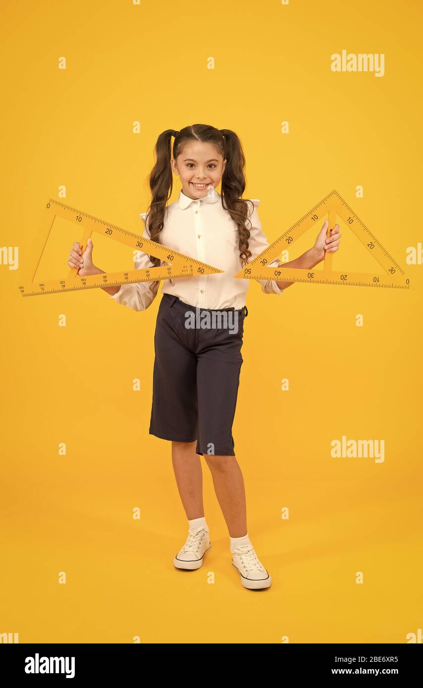 Ruler makes the drawing look better. Small child holding drawing instrument  on yellow background. Little girl using ruler for drawing straight lines.  Having geometry or technical drawing lessons Stock Photo - Alamy