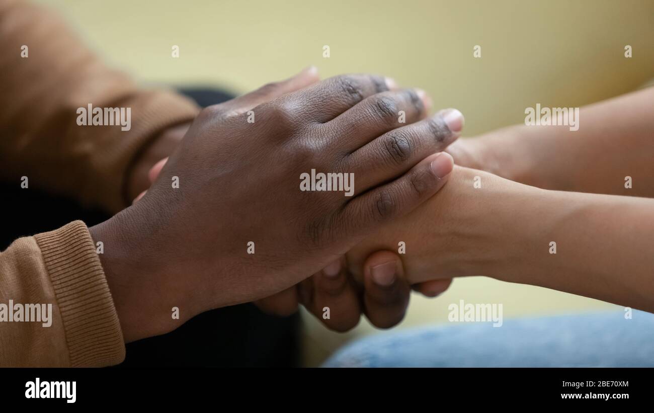 Close up african american man hands holding upset depressed woman. Stock Photo