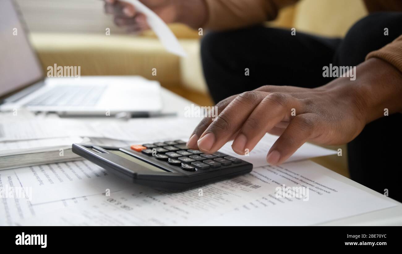 Close up black man hand using calculator and laptop. Stock Photo