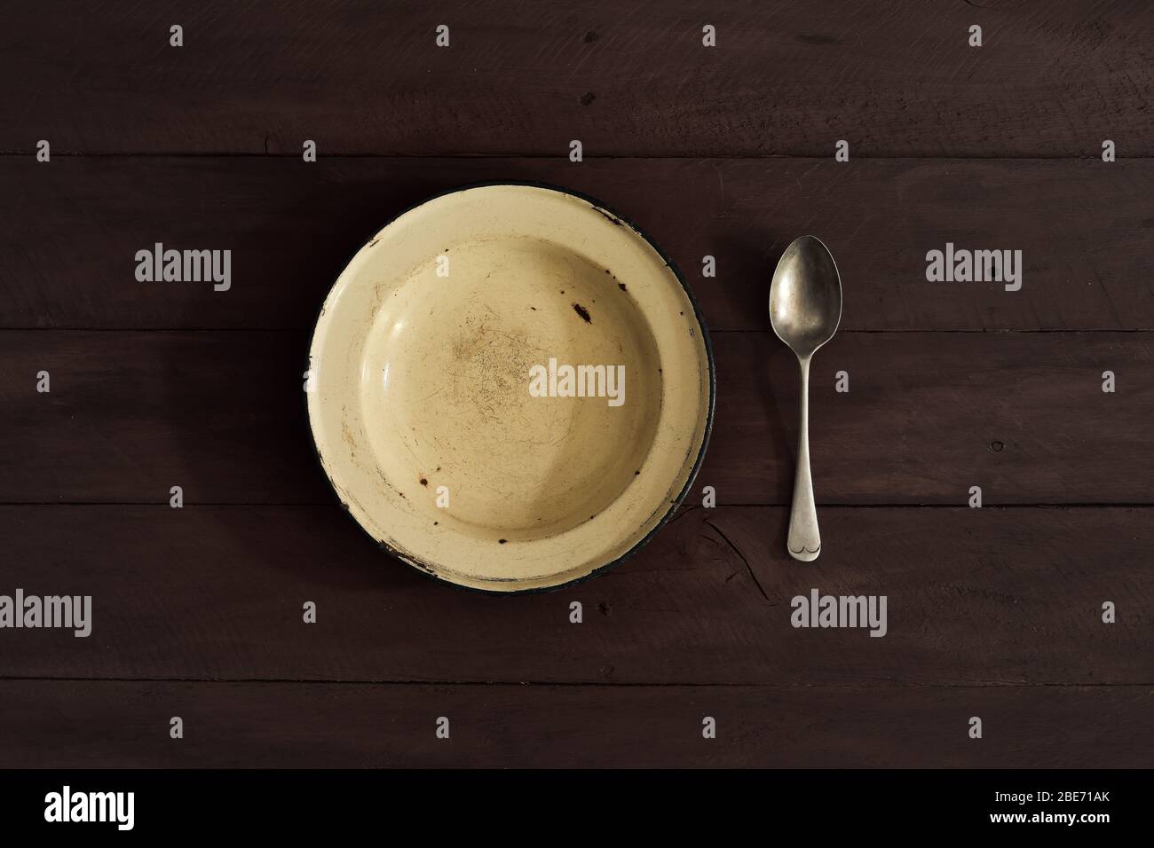 enamelled plate and spoon on wooden table Stock Photo