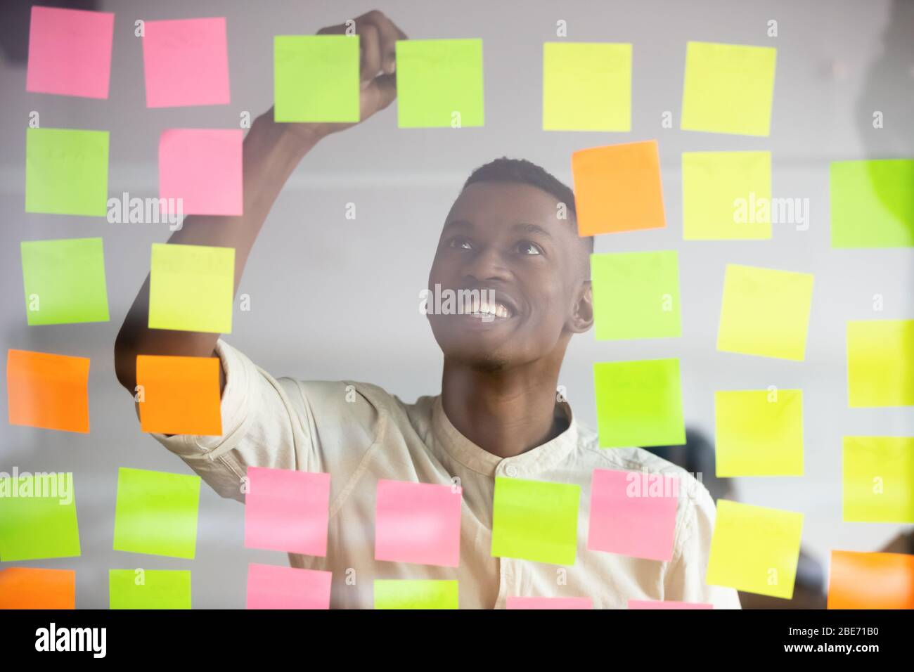 Smiling biracial man write on colorful notes developing startup Stock Photo