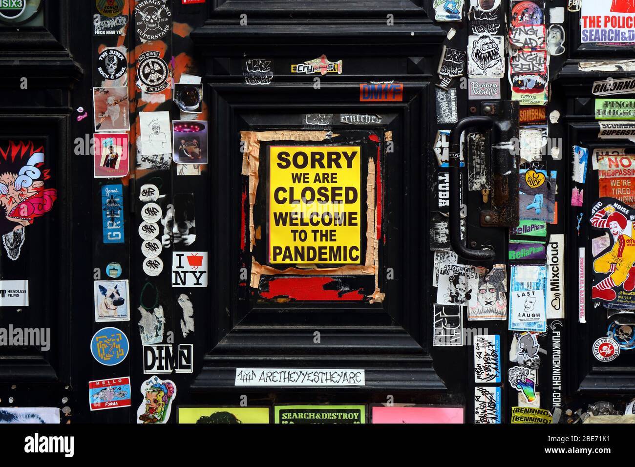 'Sorry We Are Closed Welcome To The Pandemic' sign with stickers on a door in the East Village neighborhood of Manhattan, New York, NY during covid 19 Stock Photo