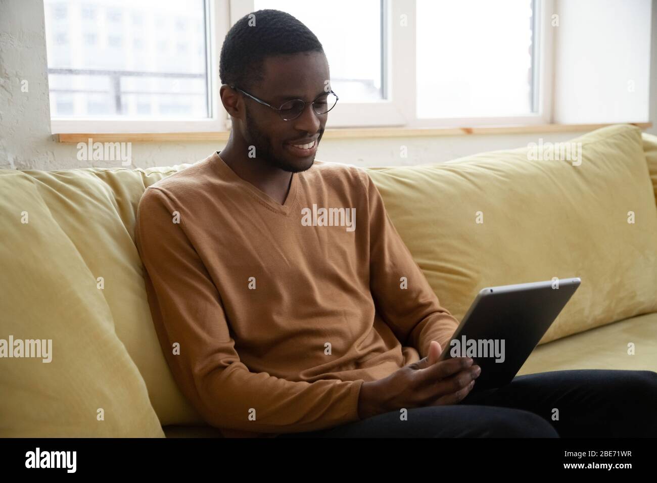 Smiling African American man holding and using tablet. Stock Photo
