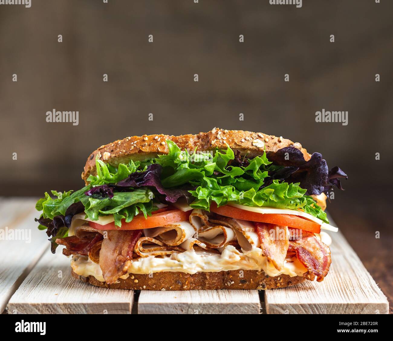 BLT sandwich on wooden surface with linen backdrop Stock Photo