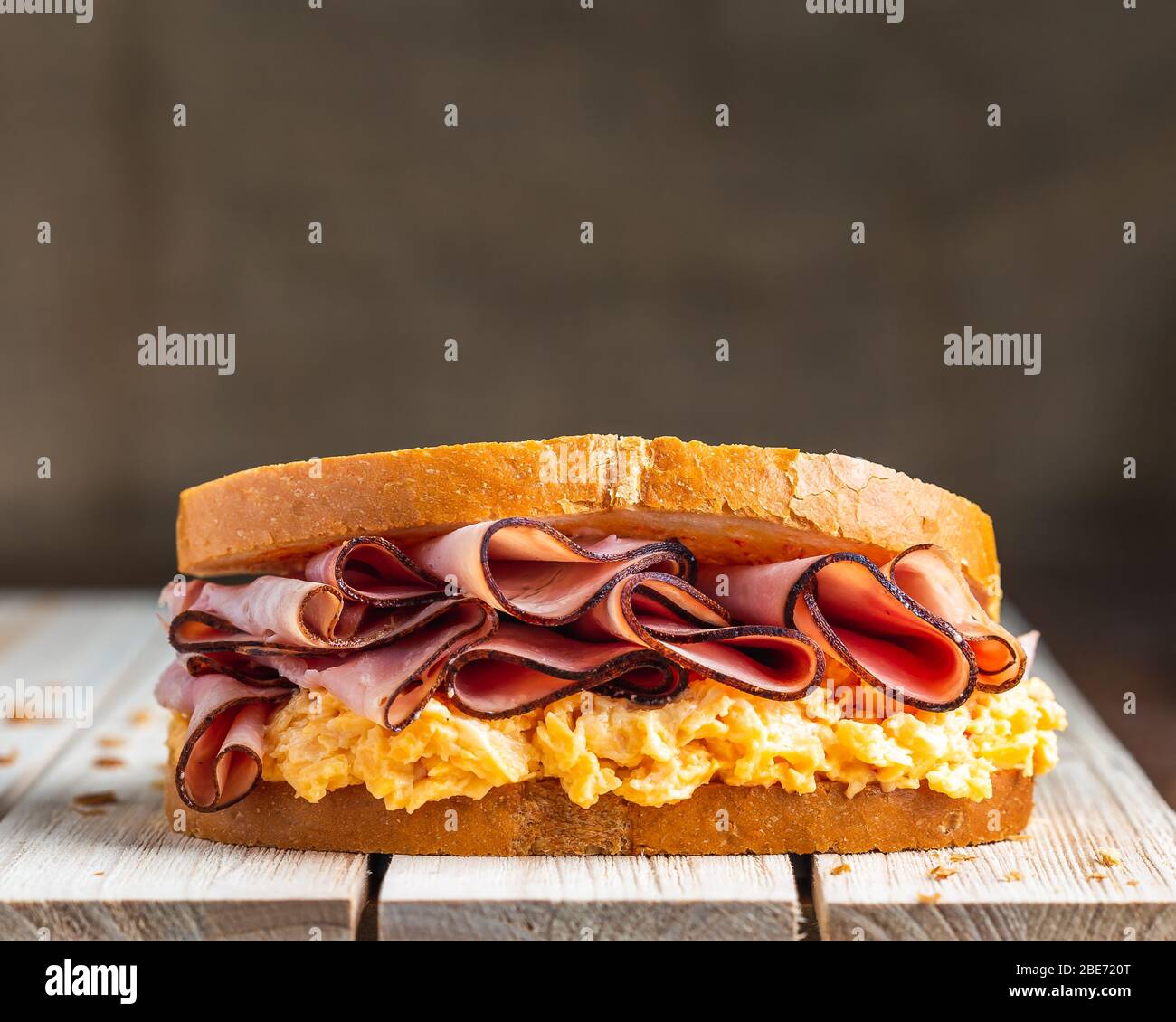 Ham and cheese sandwich on wooden surface with linen backdrop Stock Photo