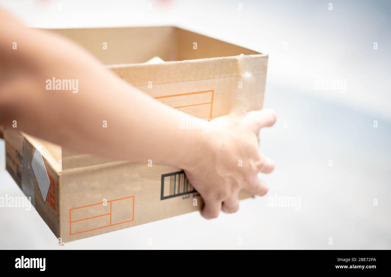 Delivery man hand carrying wrap cardboard box packaging for logistic