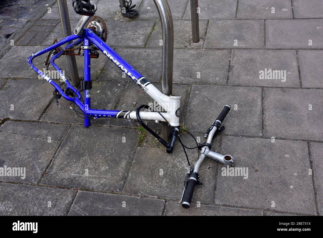 Vandalized bicycle stripped of most of its removable parts while locked up on public street now abandoned Stock Photo