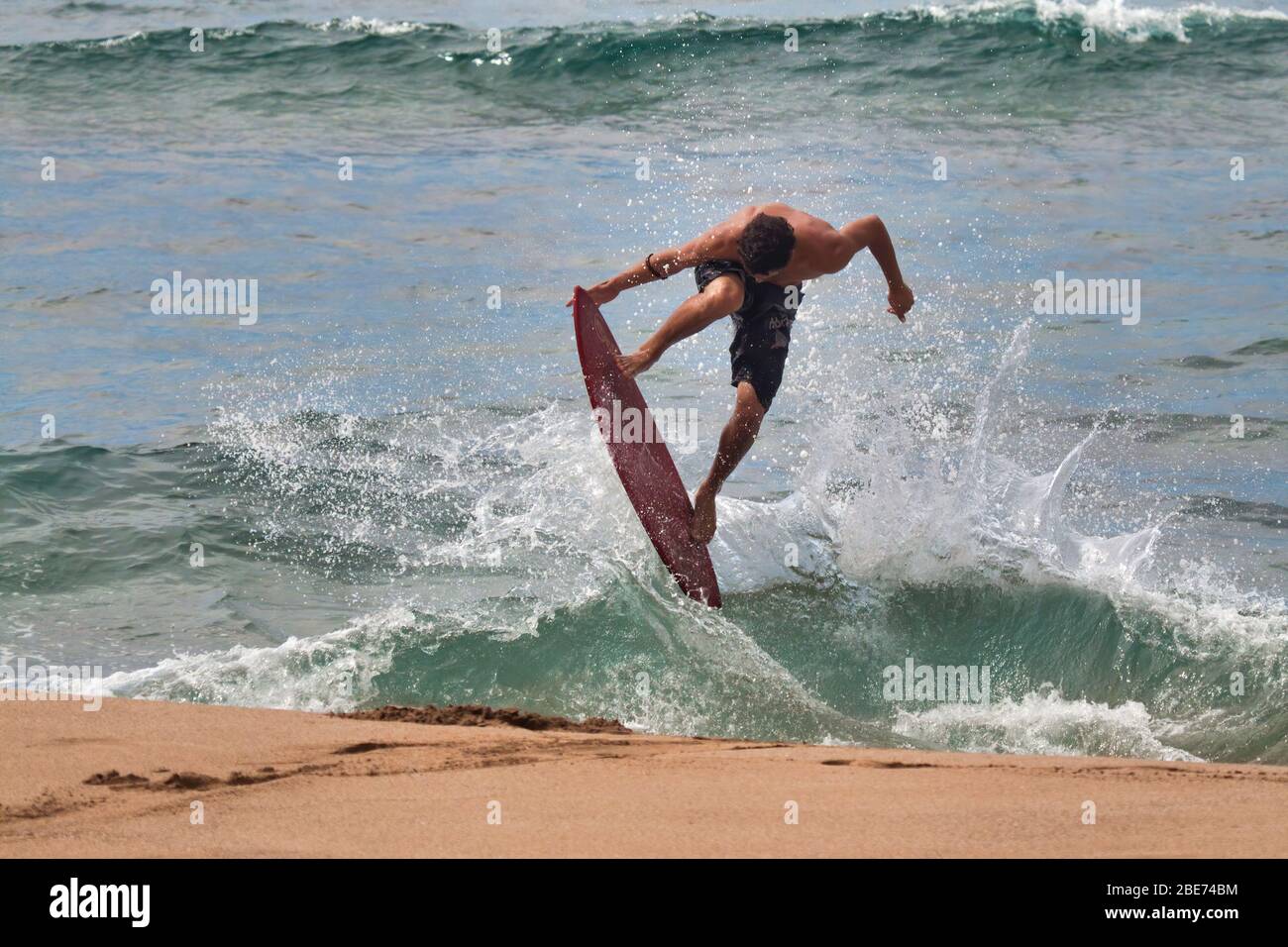 High energy shot of a young male on a skim board at the beach. Stock Photo