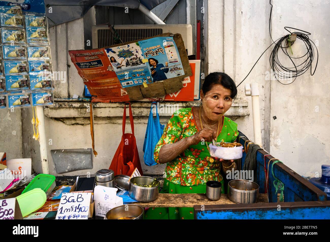 Woman eating lunch at her outdoor stall, Yangon, Myanmar Stock Photo