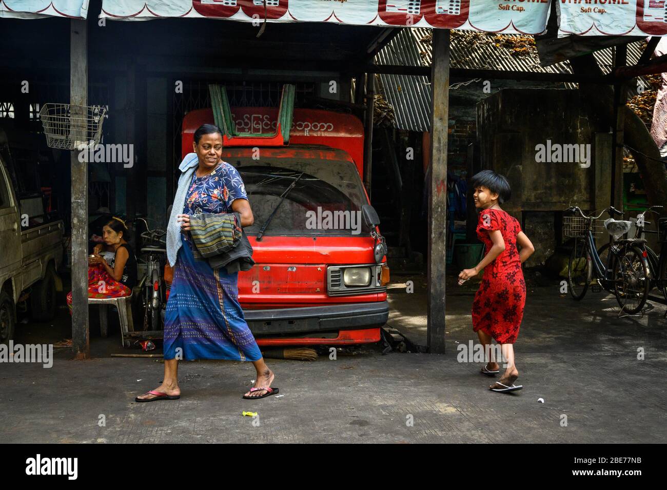 Neighborhood exchange between a woman and young girl, Yangon, Myanmar Stock Photo