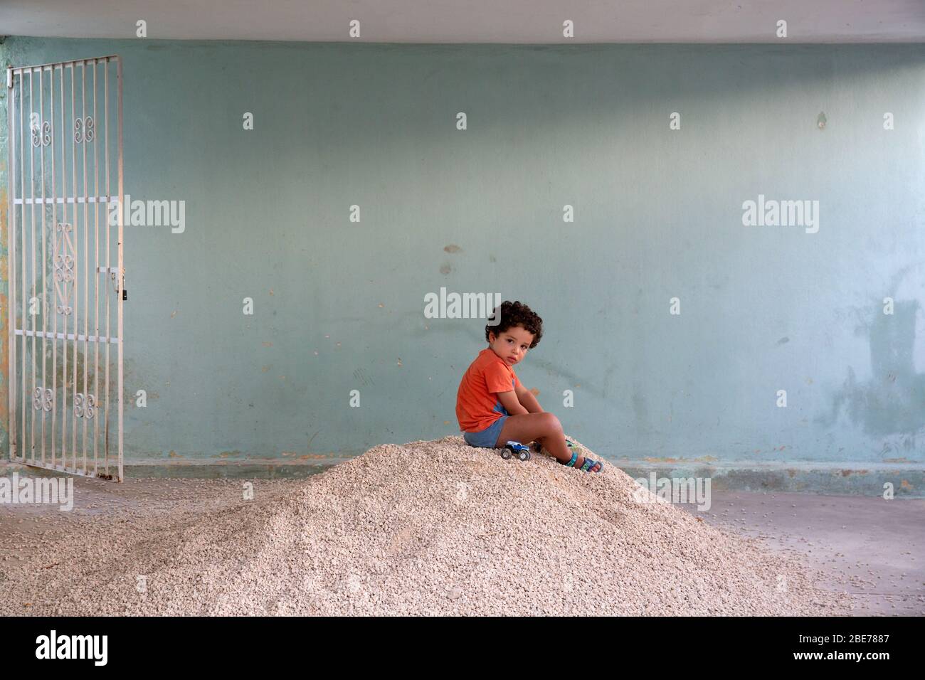 Thiago playing alone on a pile of gravel on his eighteenth day of self-isolation due to Covid-19 pandemic at a temporary home in Mérida, Yucatán, Mexico on April 1, 2020. Thiago, 3-years-old, is the son of the photographer. He was documented as part of a project titled “When I grow up” about a child growing up on quarantine, away from other children and from the outside world, during the coronavirus pandemic. Photo by Bénédicte Desrus Stock Photo