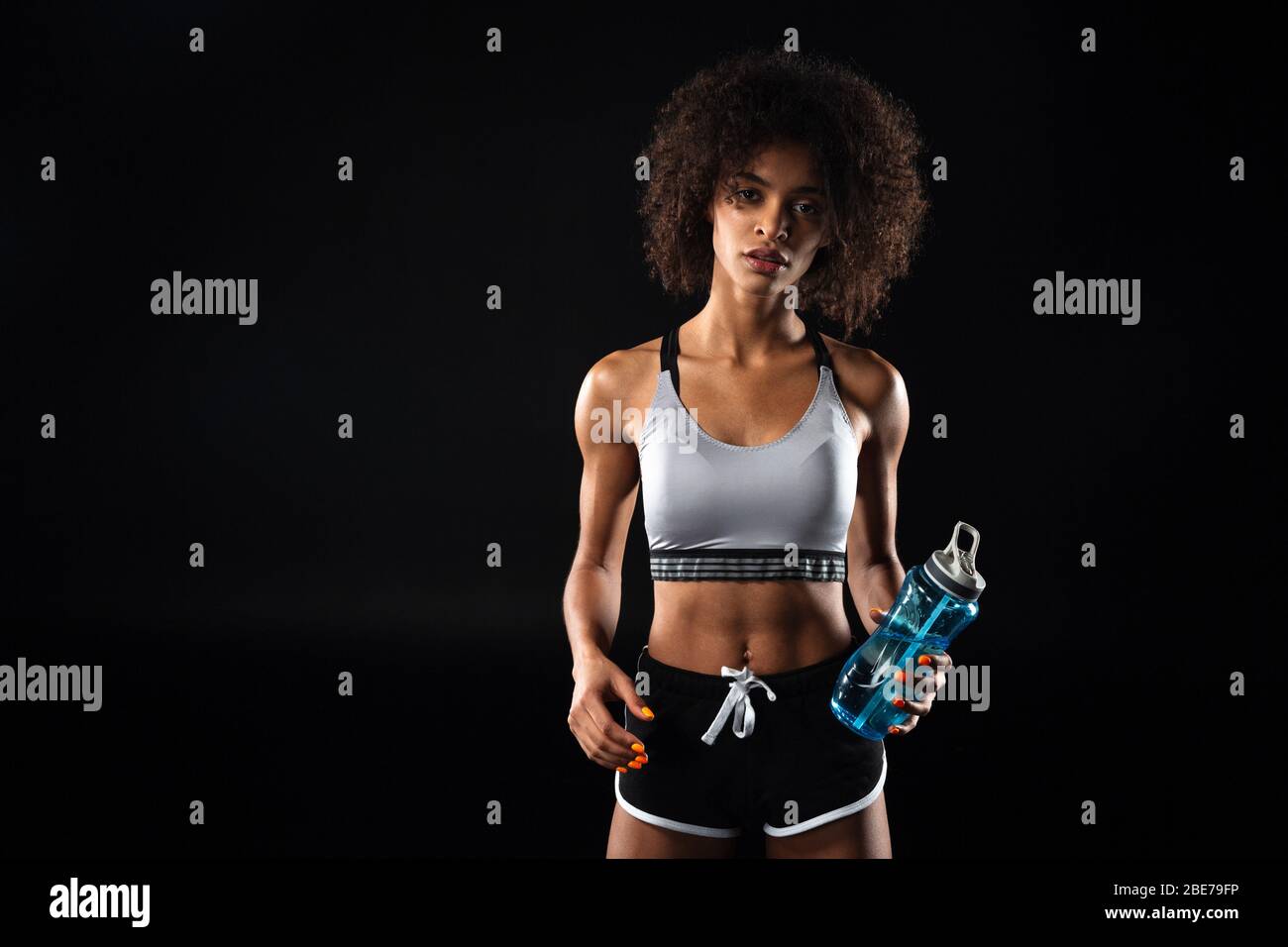 Image of beautiful african american sportswoman holding water bottle ...