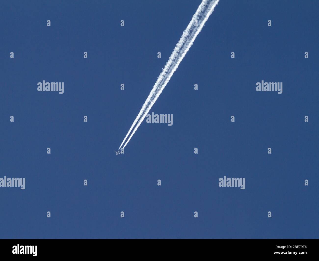 Jet contrail across clear blue sky Stock Photo