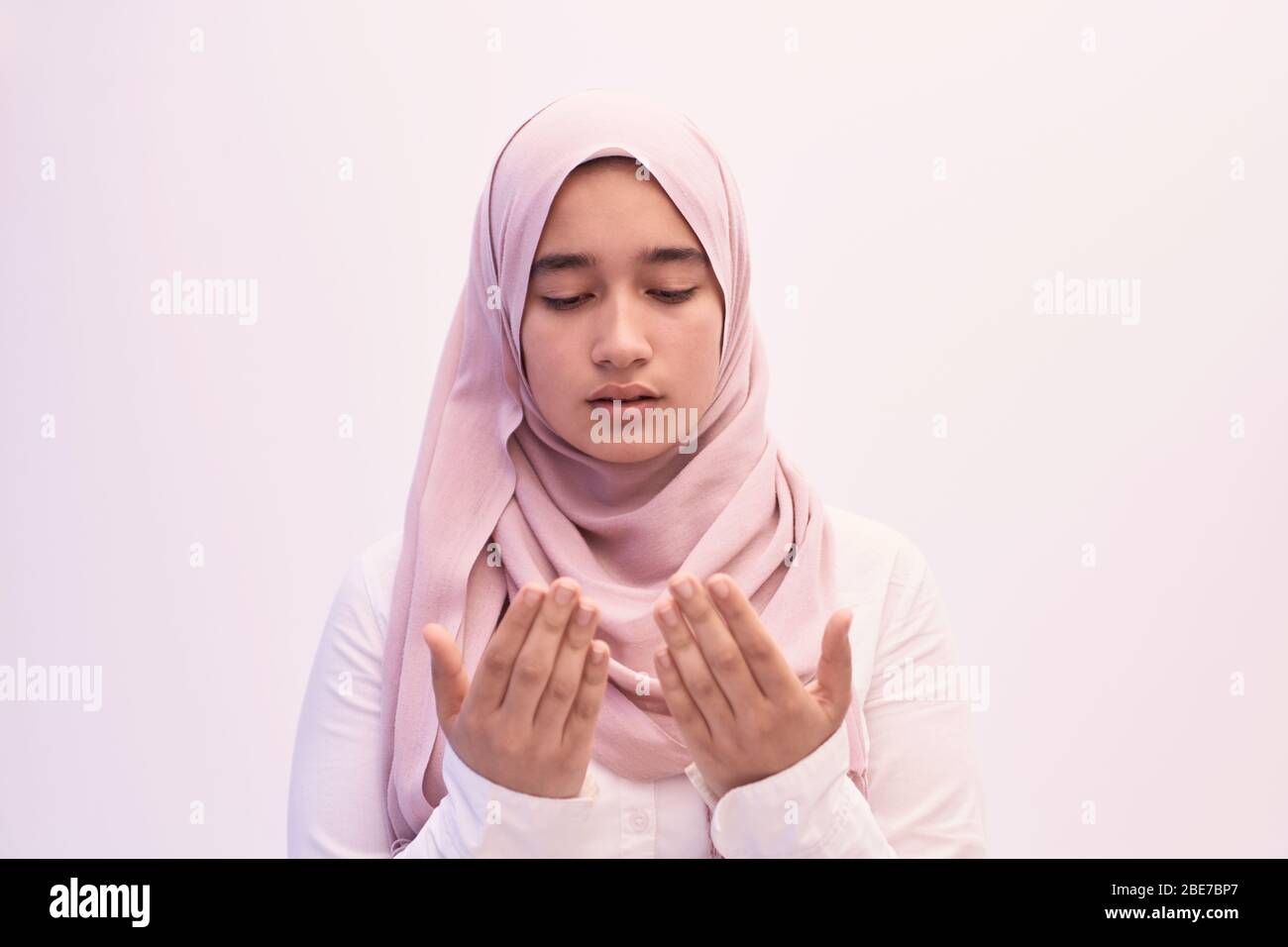 Arab female Muslim in traditional hijab clothes praying namaz dua open