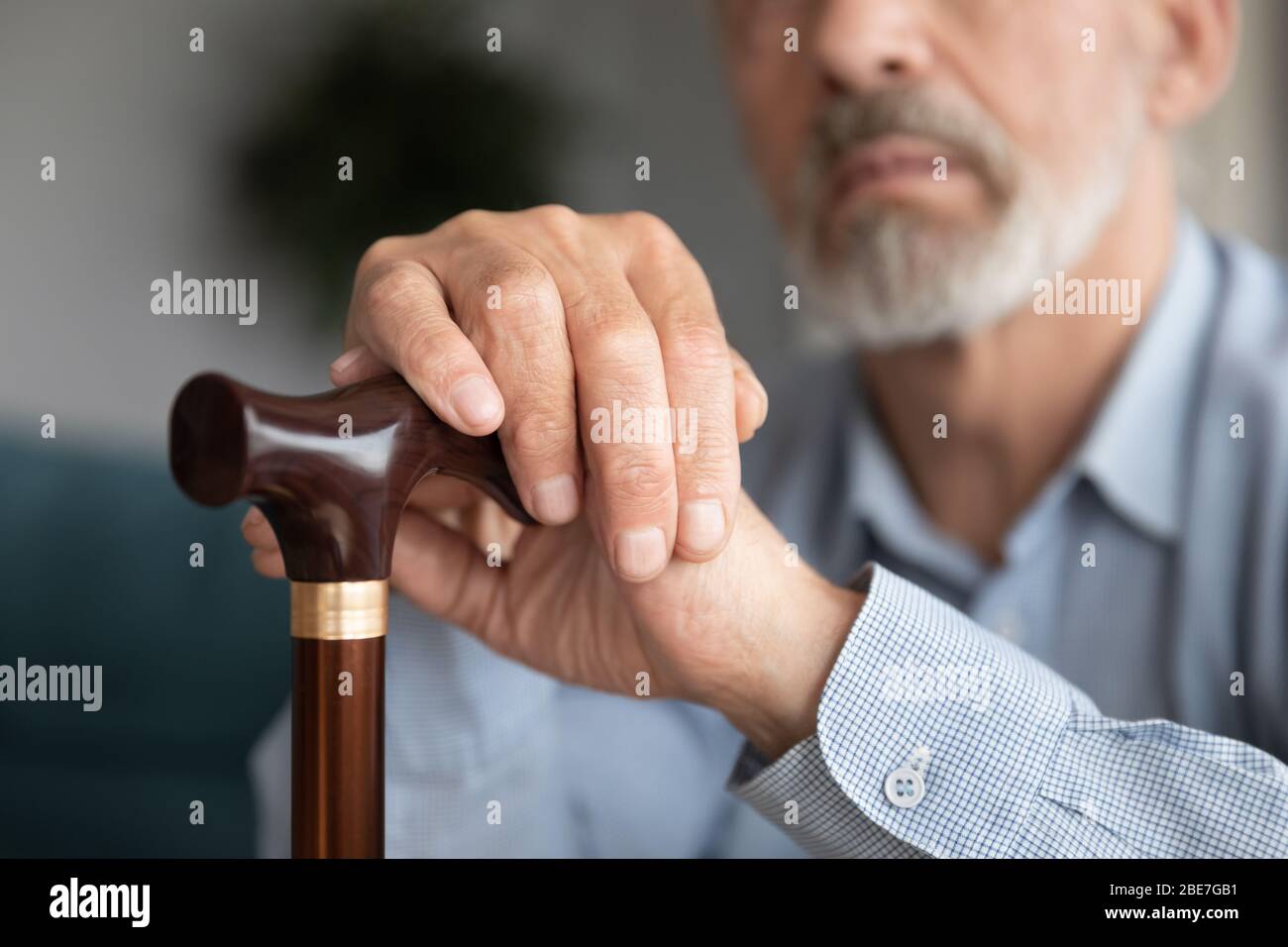 Close up mature man holding hands on wooden cane Stock Photo