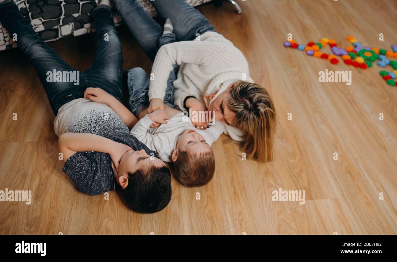 Mother and her sons play on the floor. The family is having fun  Stock Photo