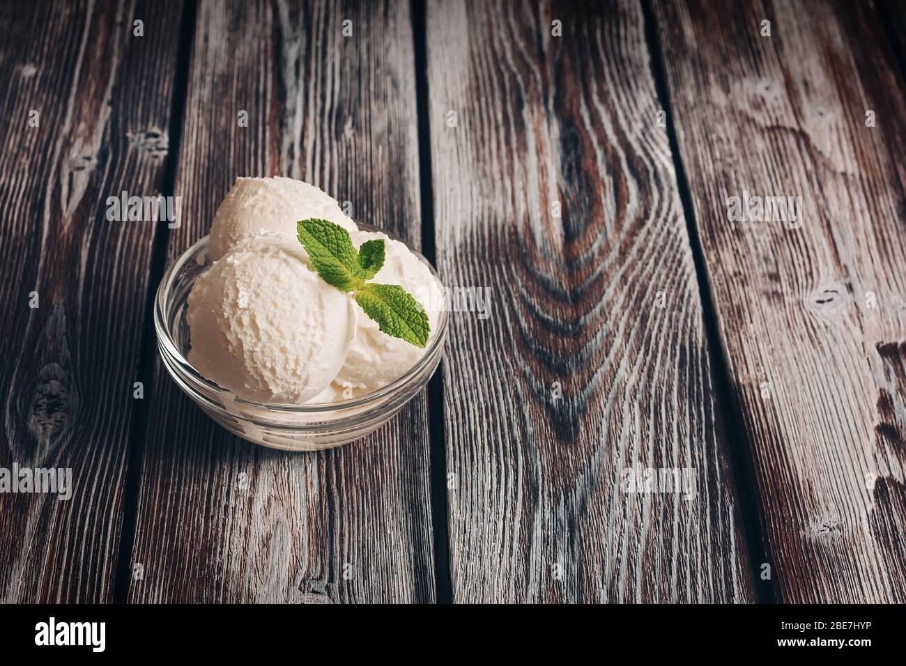 ice cream with mint in a glass bowl and strawberry on plaid fabric