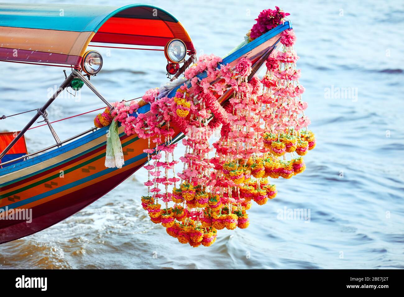 Traditional Thai longtail boat with flower garland close up in Chao Phraya river in Bangkok Stock Photo