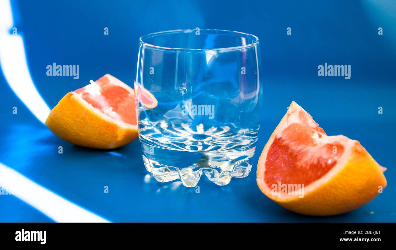 grapefruit juice with empty glass on blue background, citrus fruits