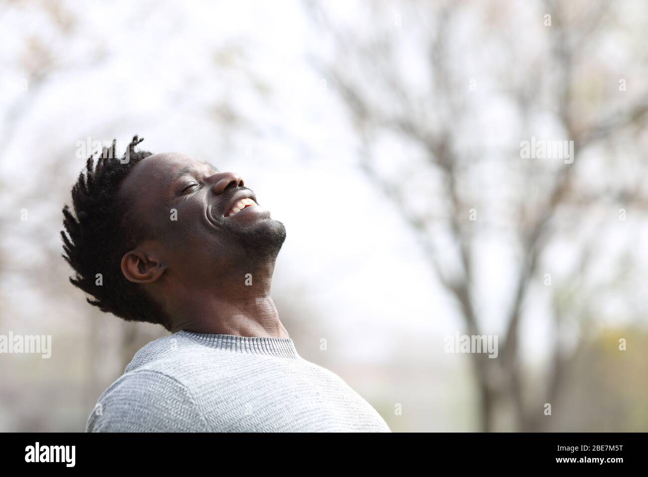Happy black man breathing fresh air outdoors in winter standing in a park Stock Photo