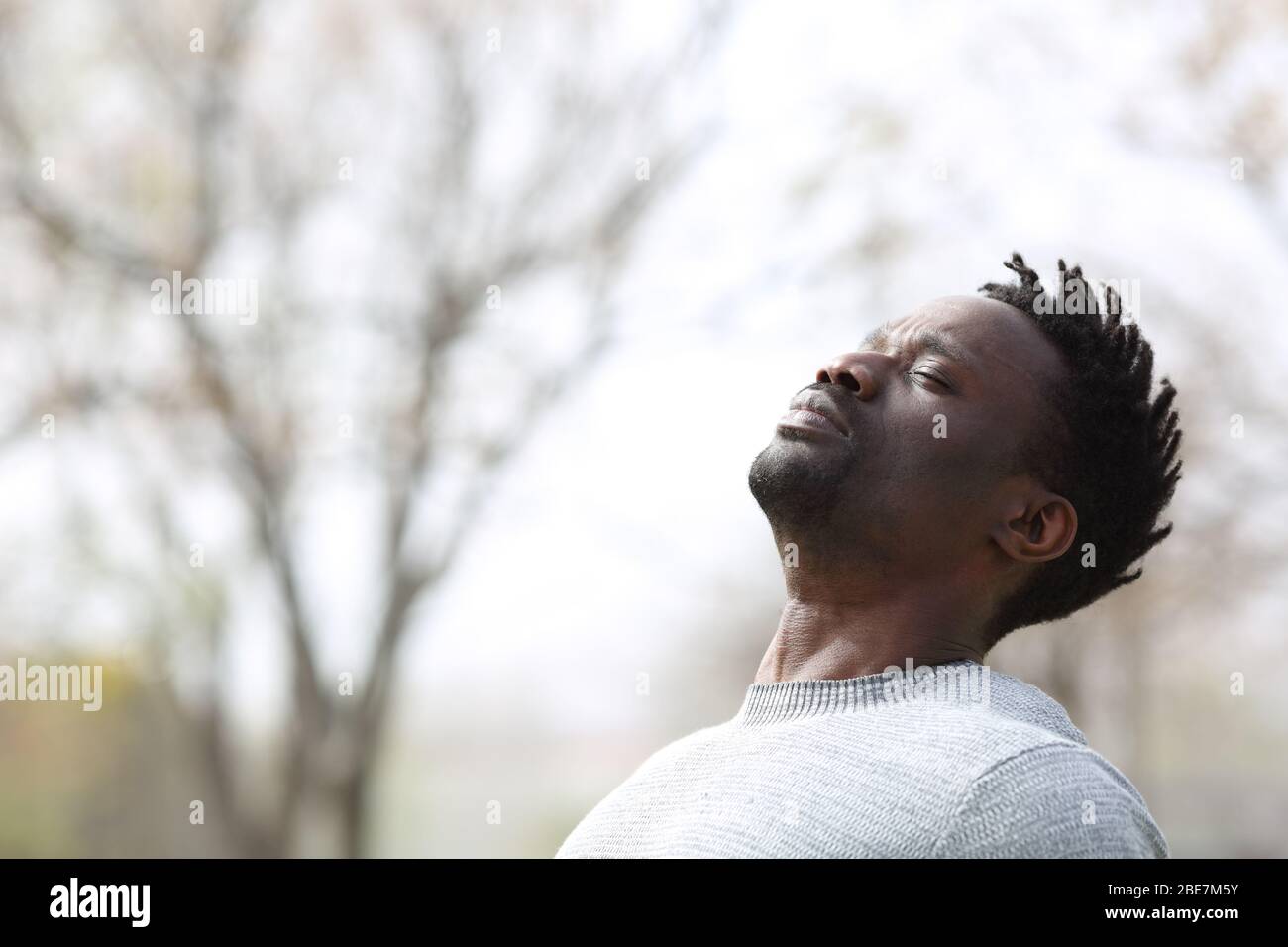 Black man breathing deep fresh air outdoors in winter in a park Stock Photo