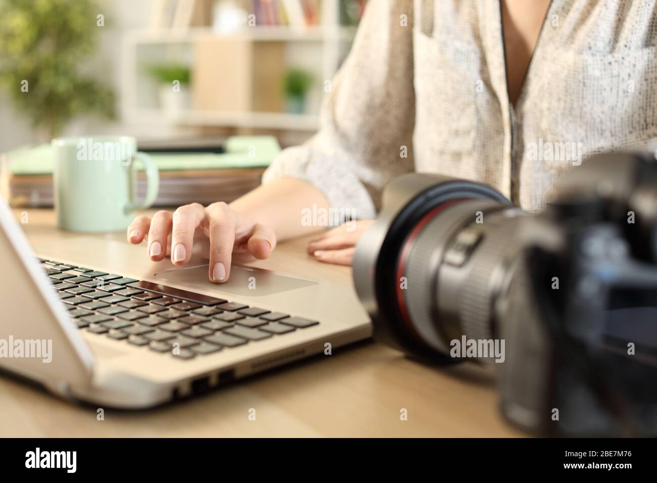 Close up of photographer woman hands connecting camera and laptop transfering files on a desk at home Stock Photo