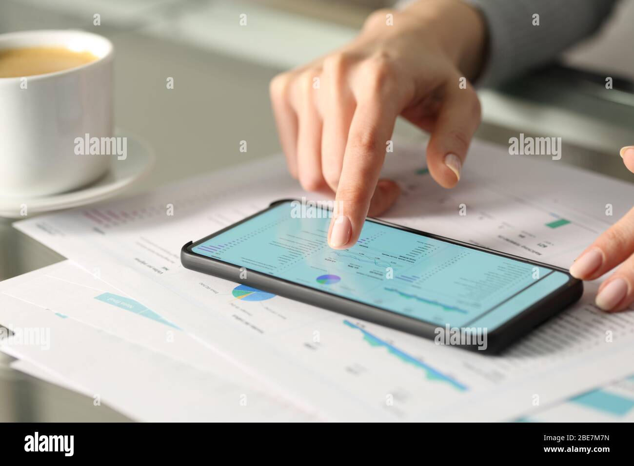 Close up of woman hands checking graphs report on smart phone on a desk Stock Photo