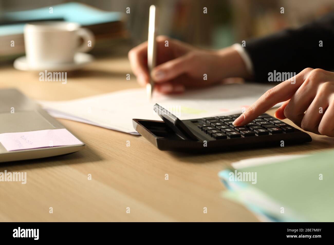 Close up of entrepreneur woman hands accounting using calculator at night on a desk at home Stock Photo