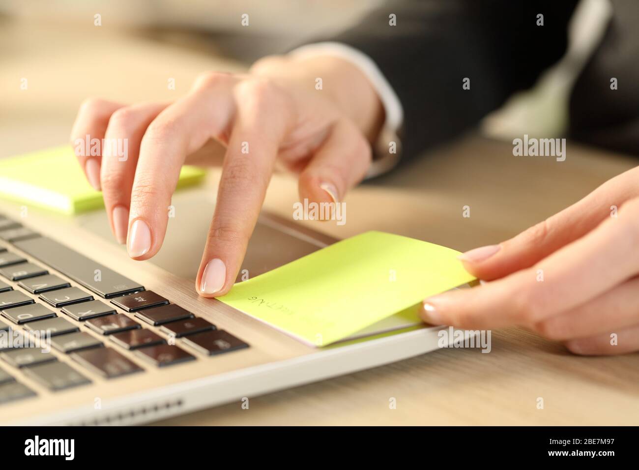 Close up of executive woman hands sticking post note over laptop sitting on a desk Stock Photo