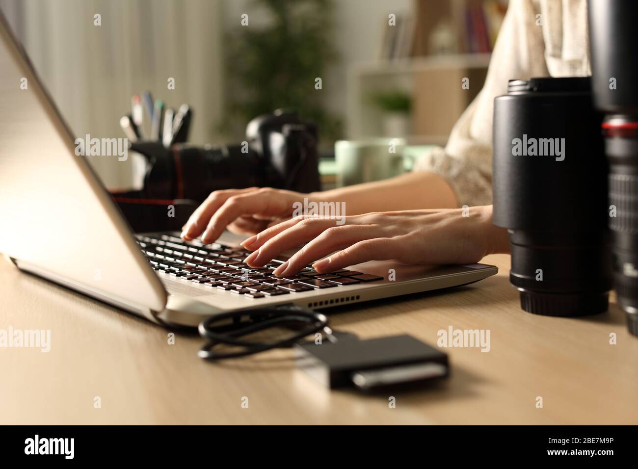 Close up of photographer woman hands transfering memory card files to laptop at night on a desk at home Stock Photo