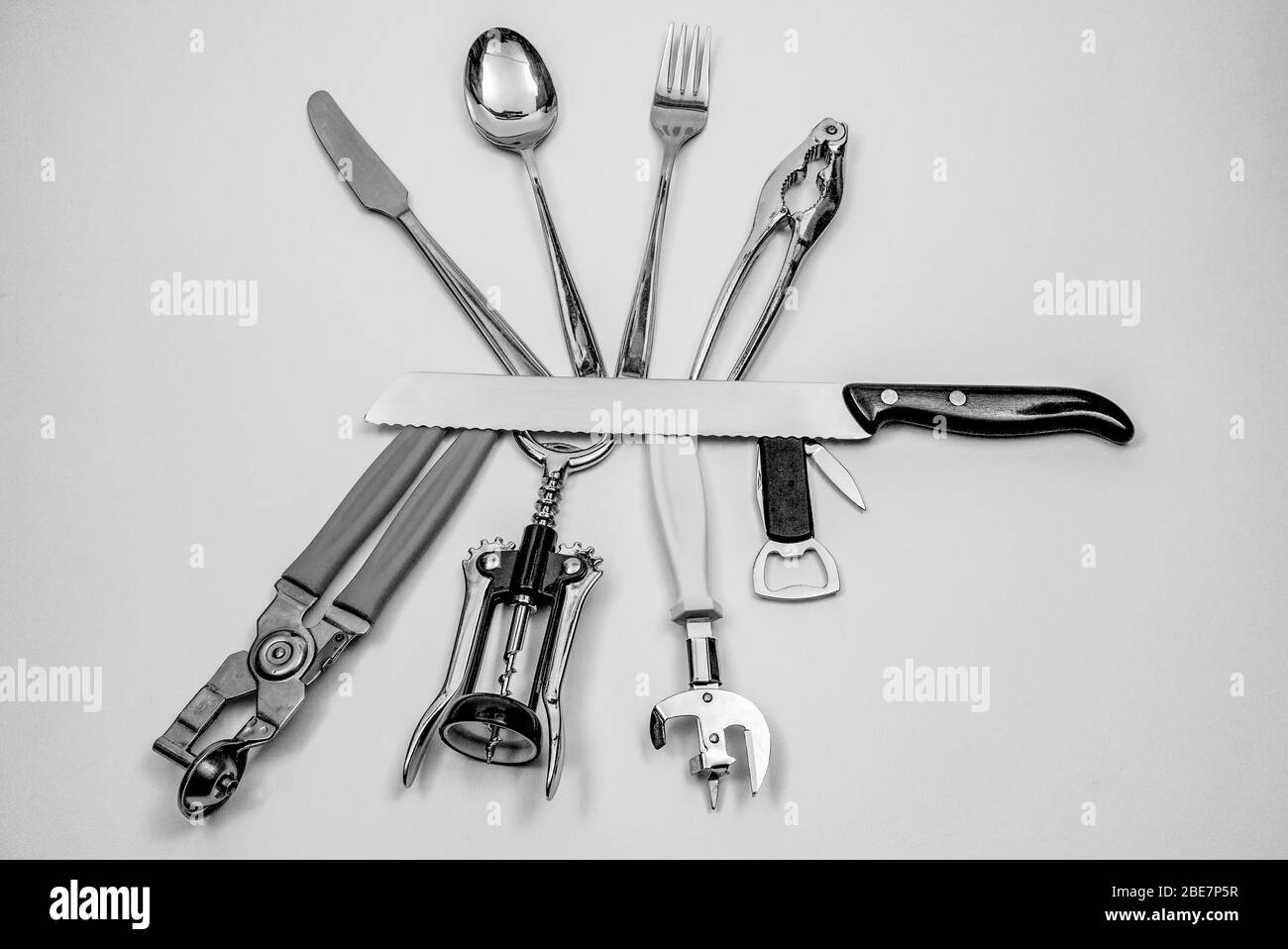 Various kitchen tools placed around a large bread knife, like a Swiss multipurpose knife Stock Photo