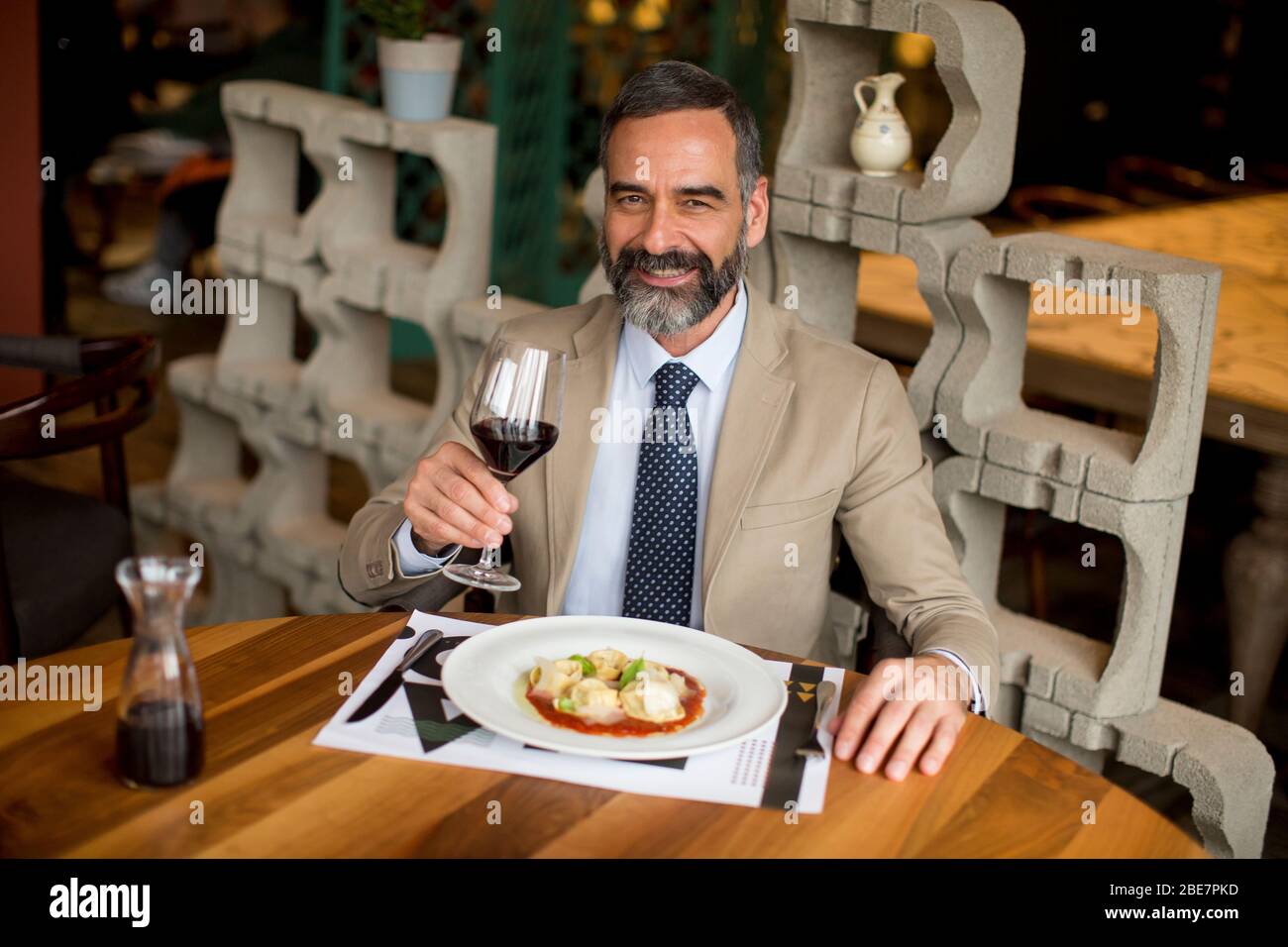 Handsome mature man drinking red wine during lunch in the restaurant