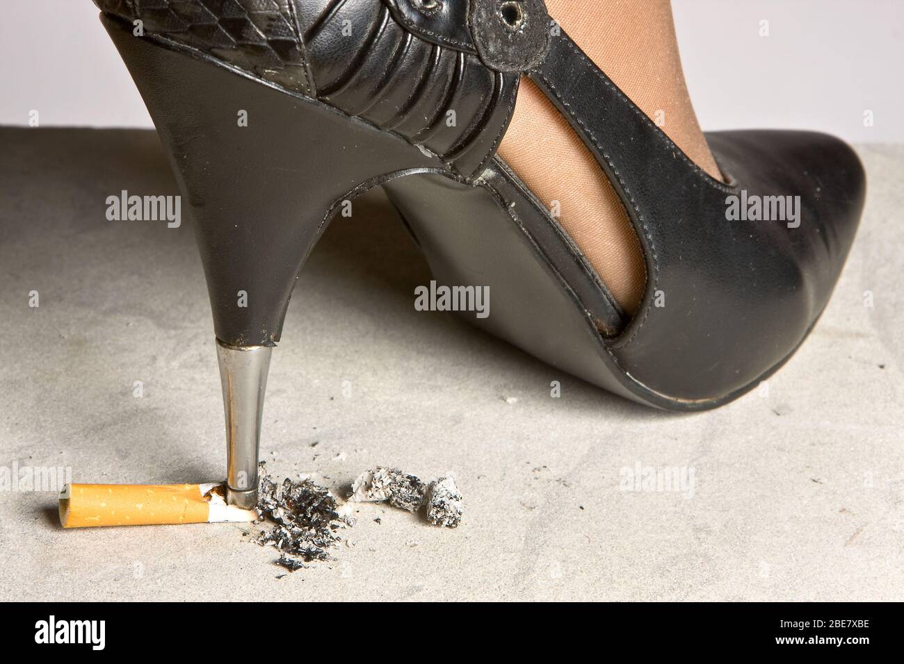 cigarette heels High-heeled stiletto shoe crushing a cigarette on the floor Stock Photo