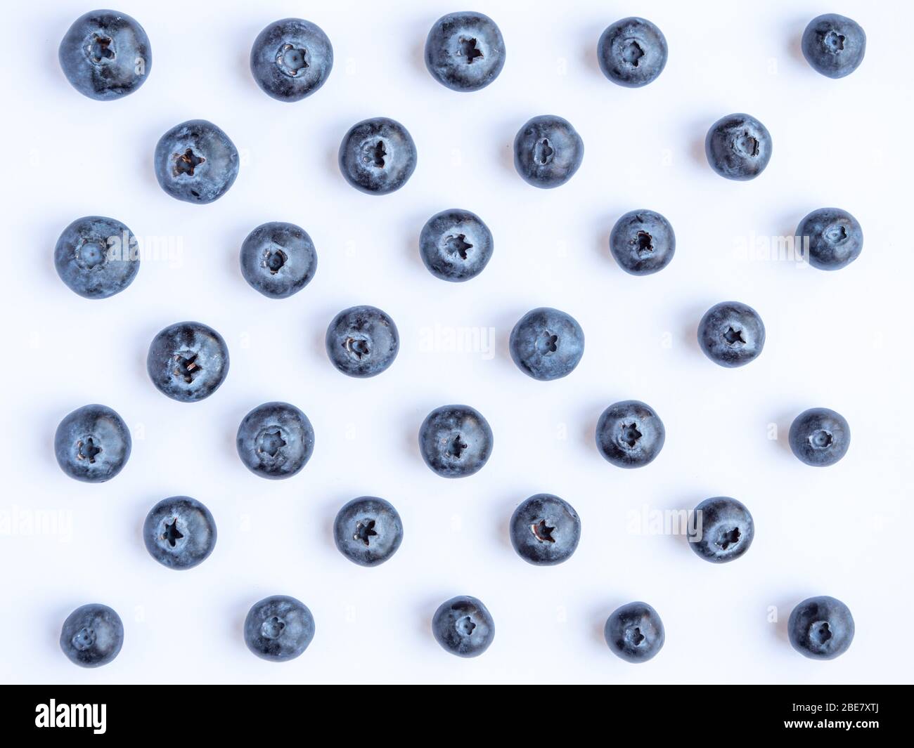 Looking down at blueberries laid out in a geometric pattern on a white background Stock Photo
