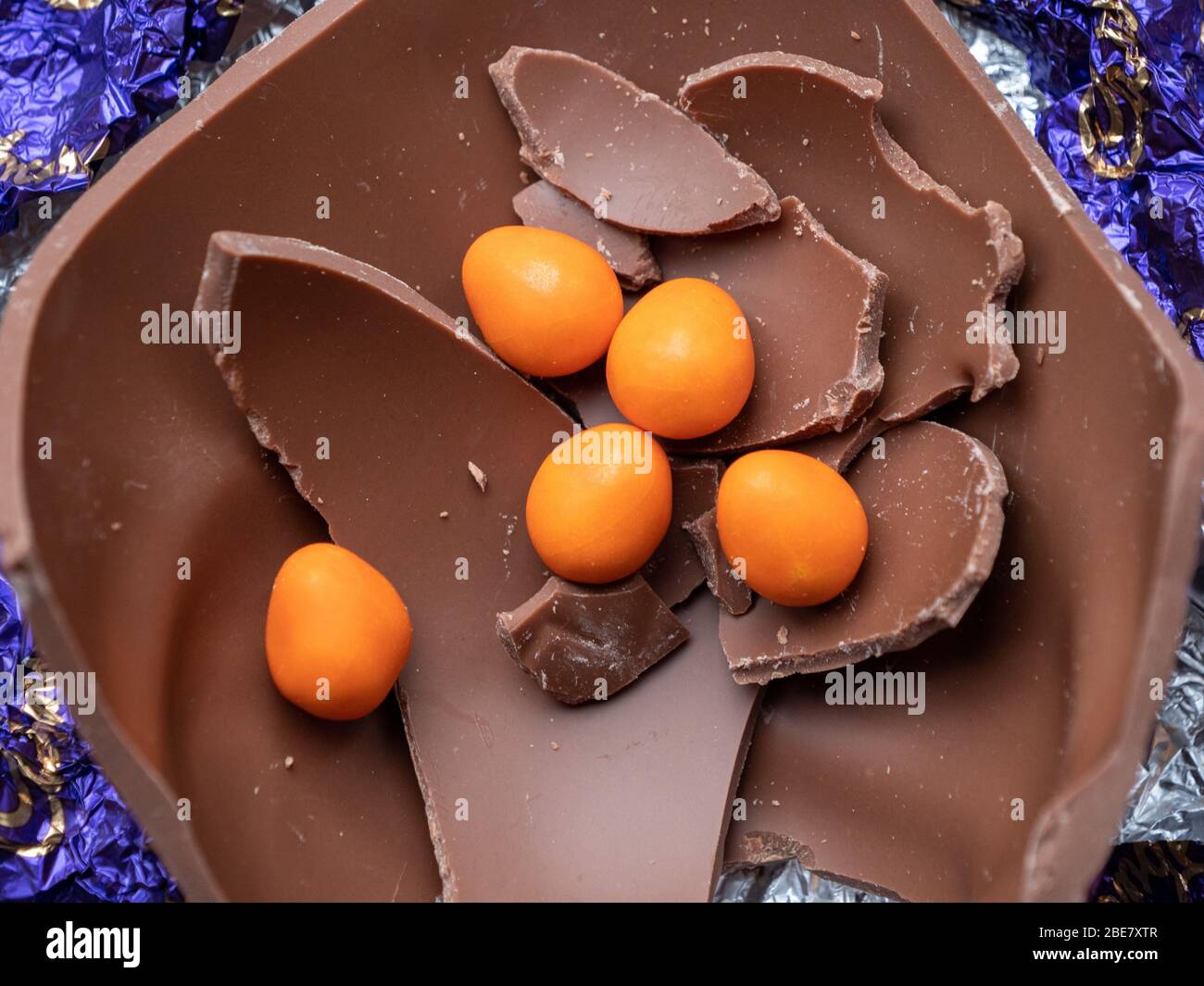 Five mini, chocolate, orange eggs inside the remains of a broken Easter egg Stock Photo