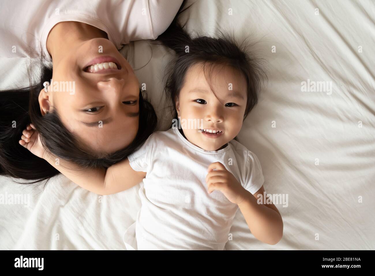 Asian mother little daughter lying on bed top above view Stock Photo