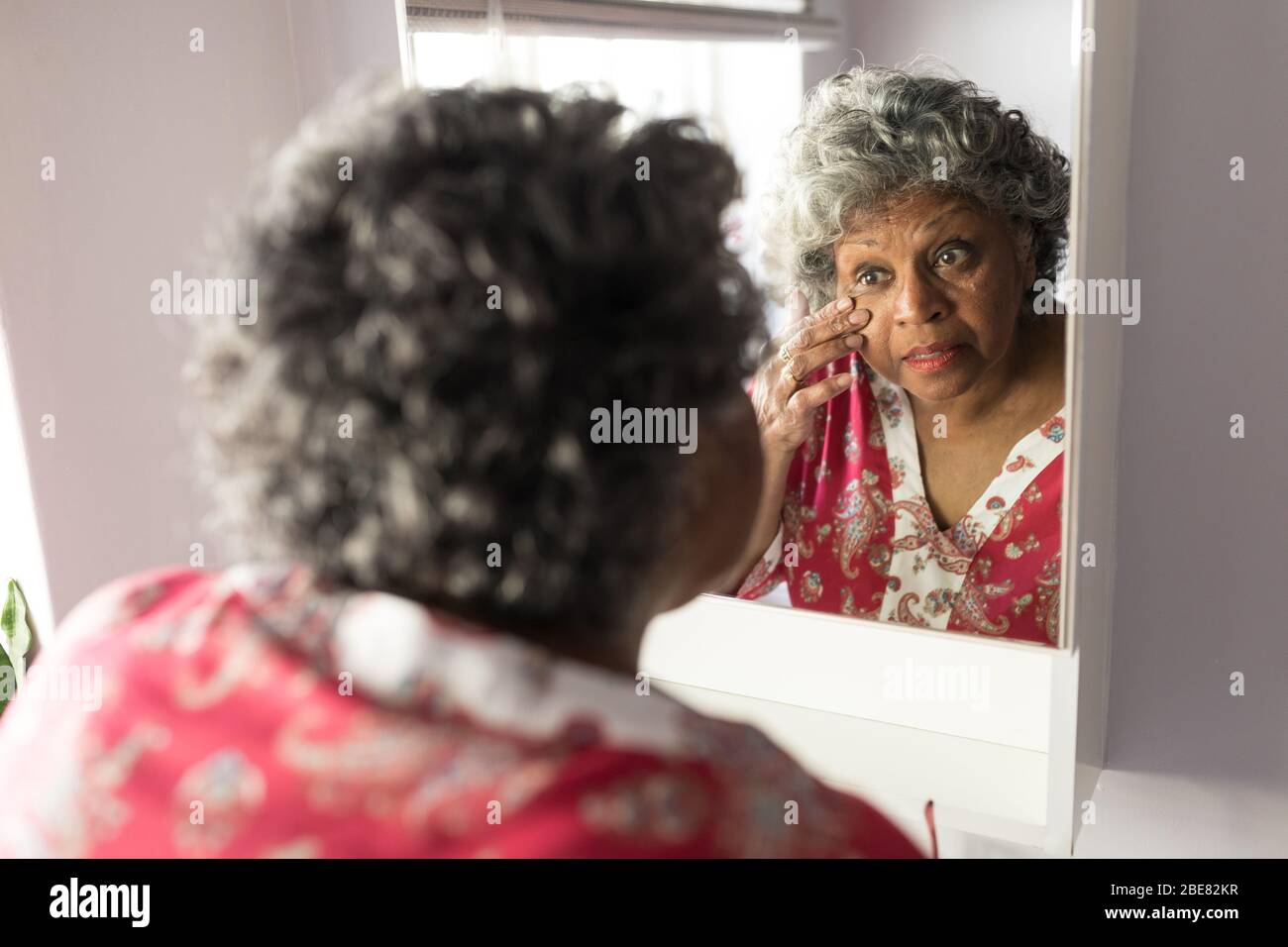 A senior African American woman looking at her reflexion in the mirror