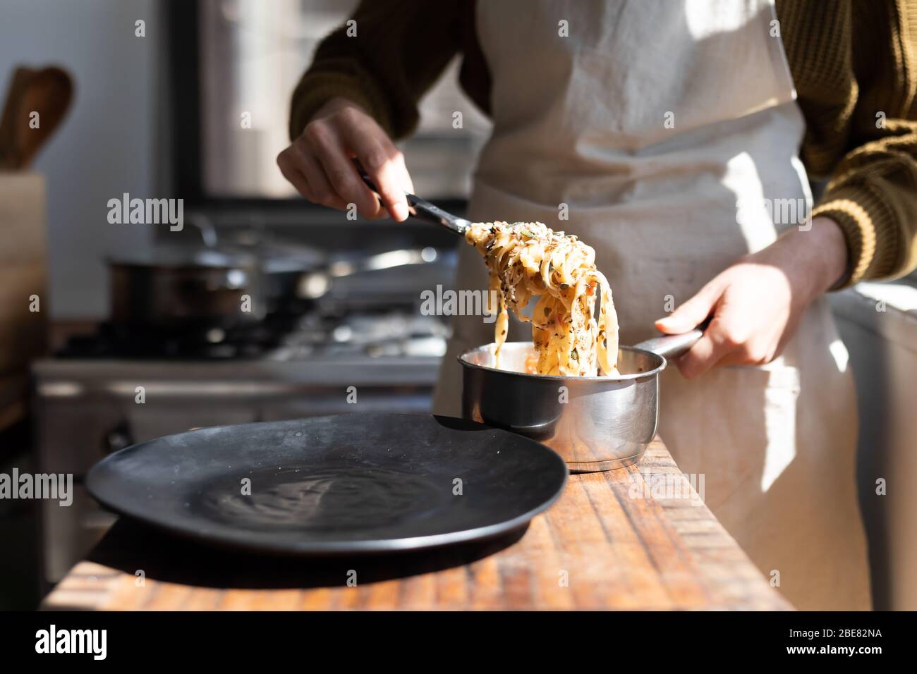 Mid section of Caucasian woman wearing an apron and presenting plate of pasta Stock Photo