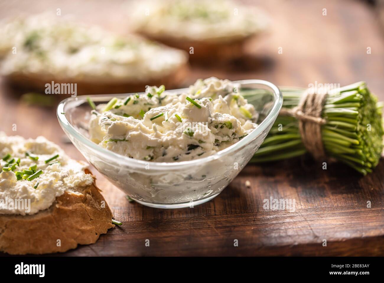 A bowl of homemade cream cheese spread with chopped chives surrounded ...