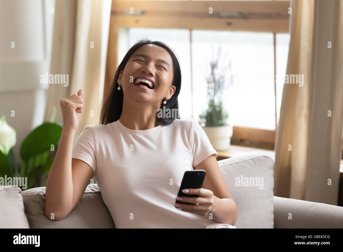 Excited vietnamese woman holding smartphone read received message feels happy Stock Photo