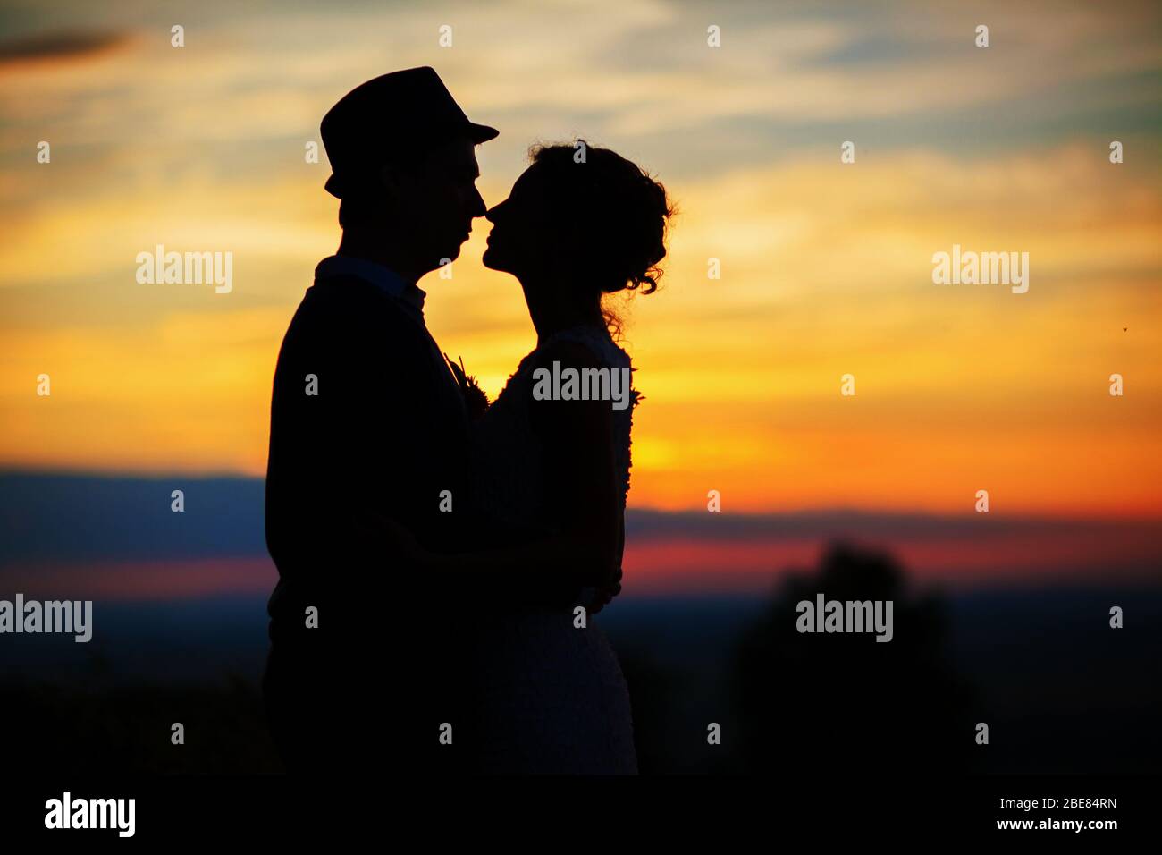 Back view of bride in white dress and groom in suit holding each others ...