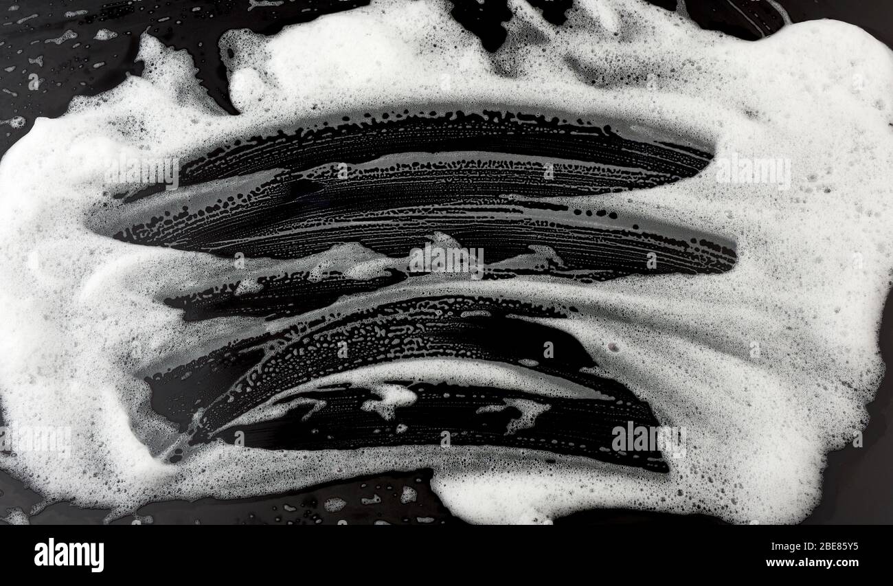 white soap foam on a black background, top view, concept of cleanliness ...
