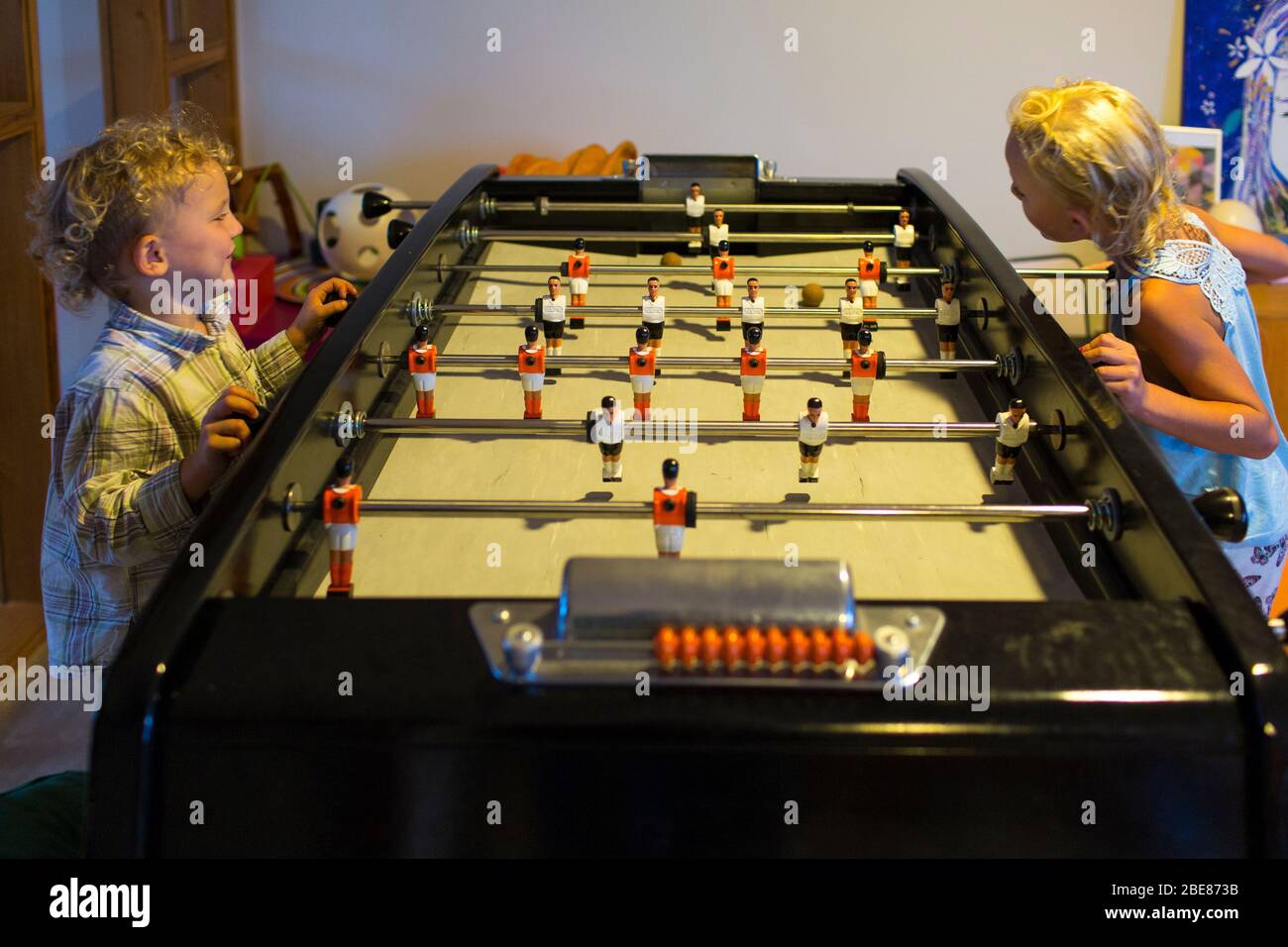 A brother and sister amuse themselves indoors playing table football in Etel, France. Stock Photo