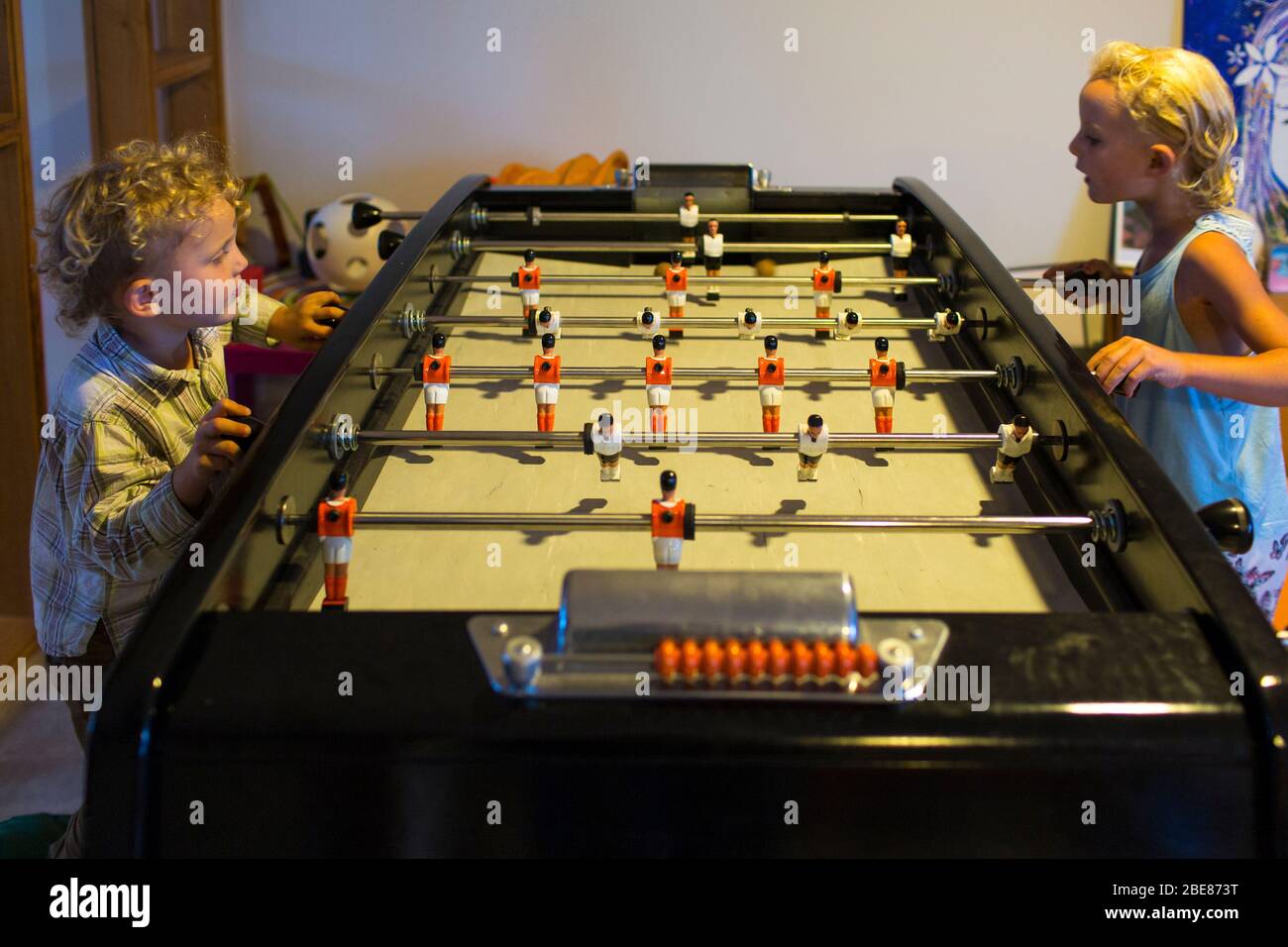 A brother and sister amuse themselves indoors playing table football in Etel, France. Stock Photo