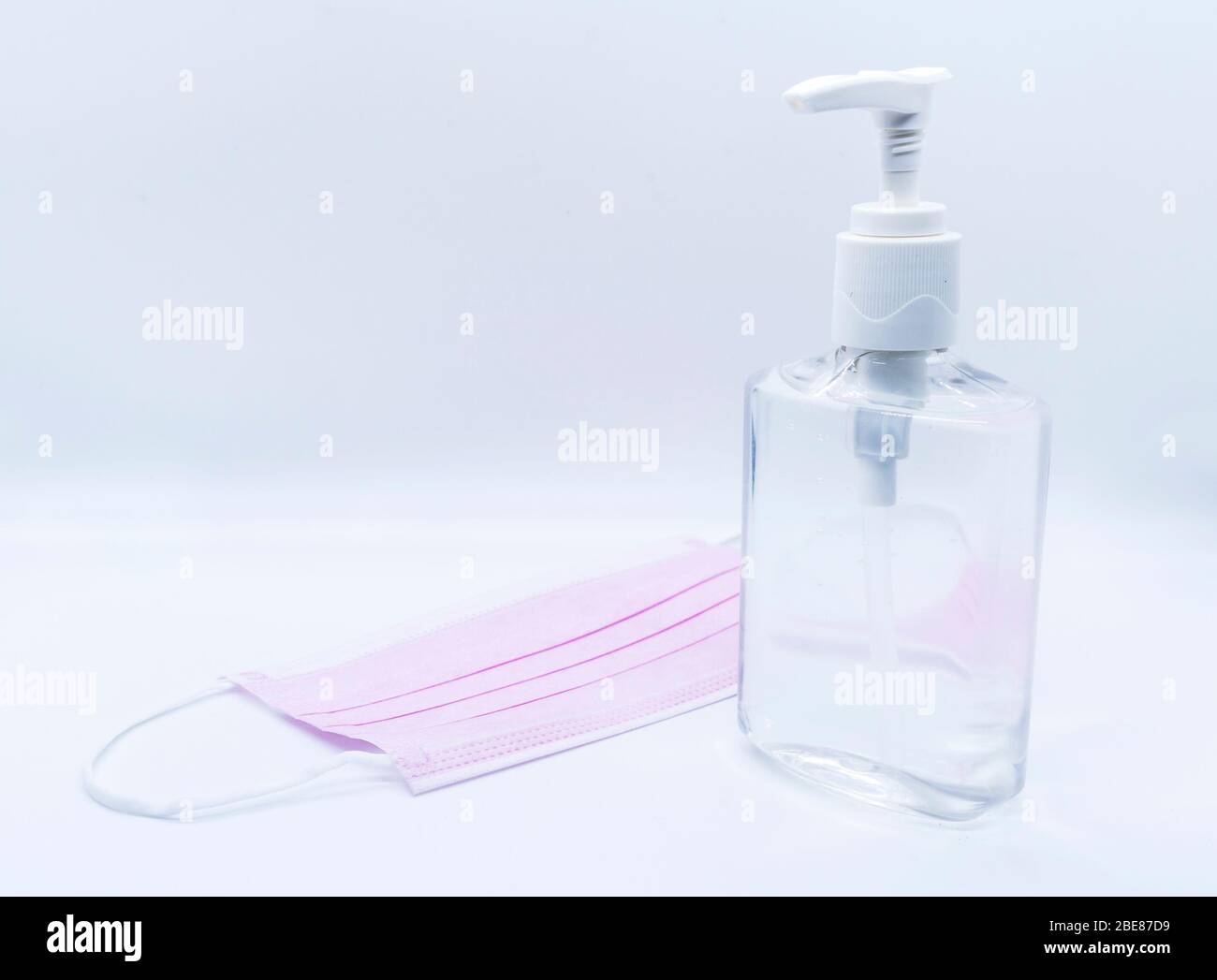 sanitizer jel bottle with pink face masks isolated on white background. Stock Photo