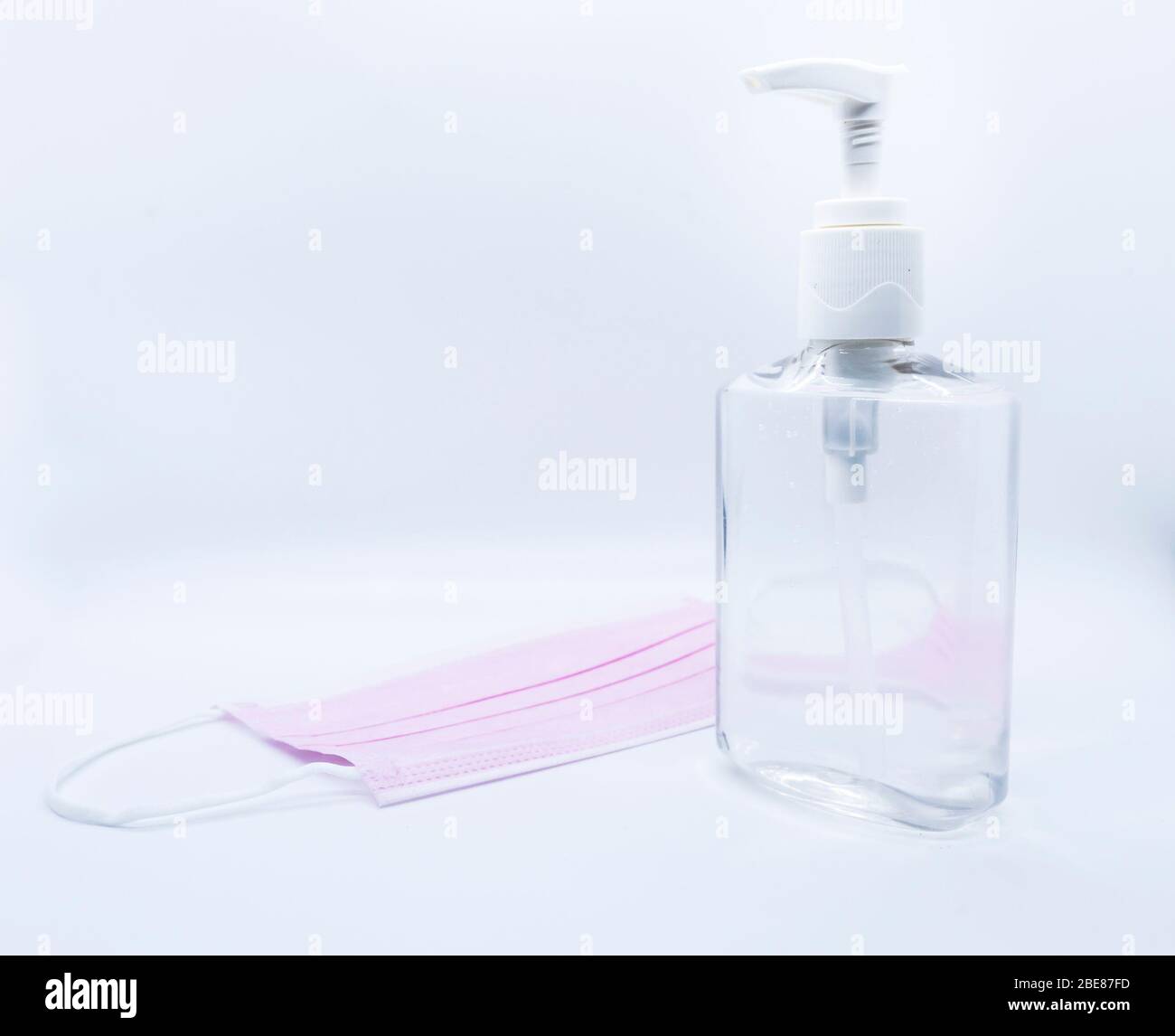 sanitizer jel bottle with pink face masks isolated on white background. Stock Photo