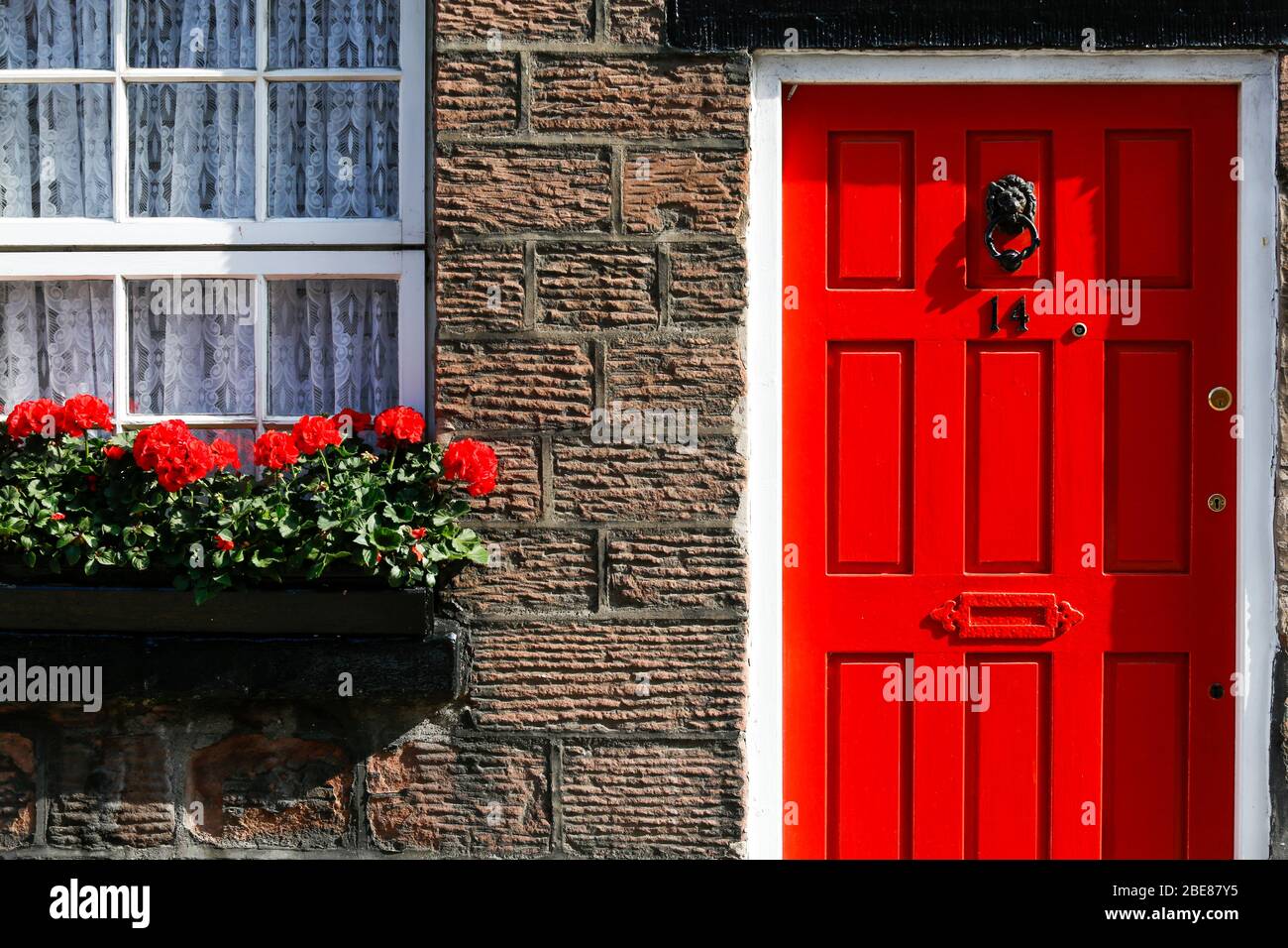 A bright red painted front door in Woolton Village, an affluent suburb of Liverpool, closely associated with the Beatles Stock Photo