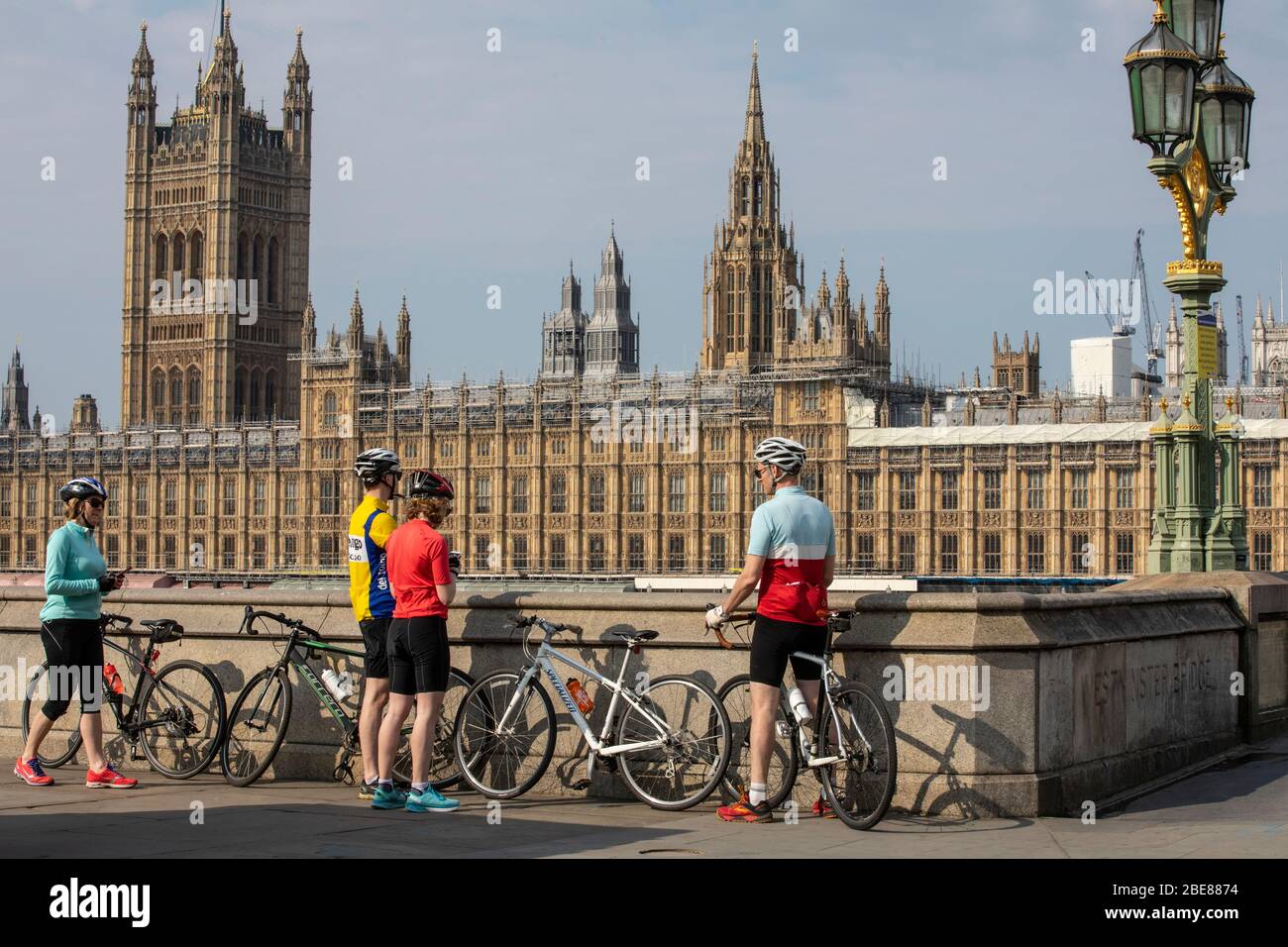 Cyclists take in the view over Houses of Parliament during the coronavirus COVID-19 lockdown which advises people to stay at home unless essential. Stock Photo