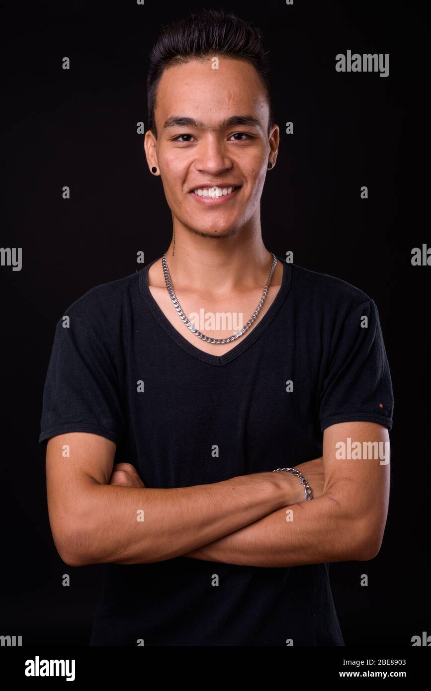Portrait of happy young handsome Indian man smiling with arms crossed ...