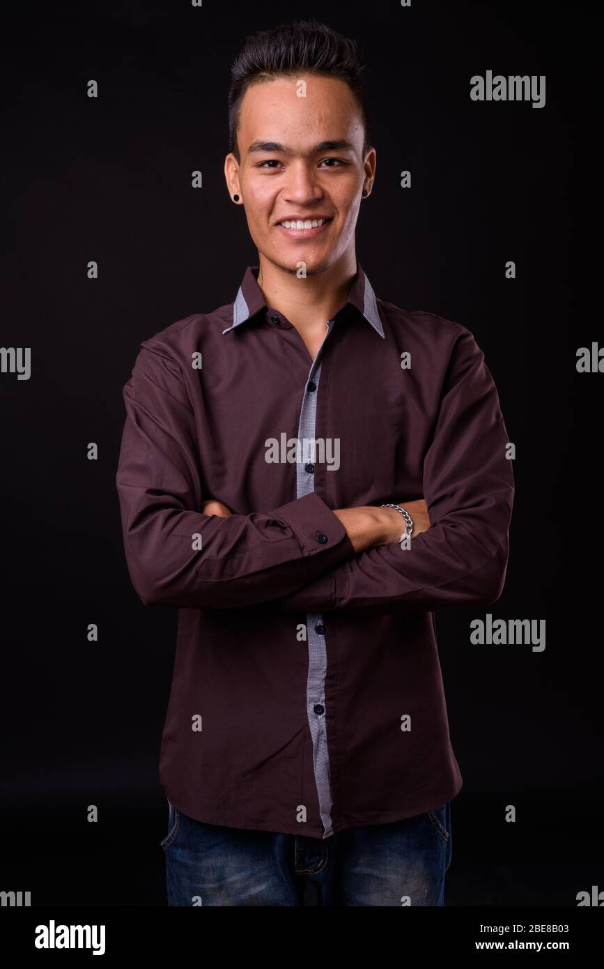 Portrait of happy young Indian businessman smiling with arms crossed ...